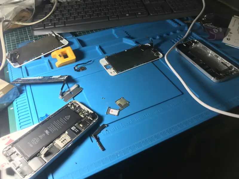 Tamir tezgahında sökülmüş iPhone'lar, ekranlar ve batarya
