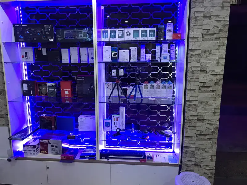 Reis Bilişim dükkânı: mavi ışıklı vitrinde telefon aksesuarları ve şarj ürünleri