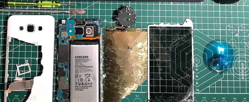 Sökülmüş Samsung telefon: kırık ekran, arka kapak, anakart ve batarya tamir matında