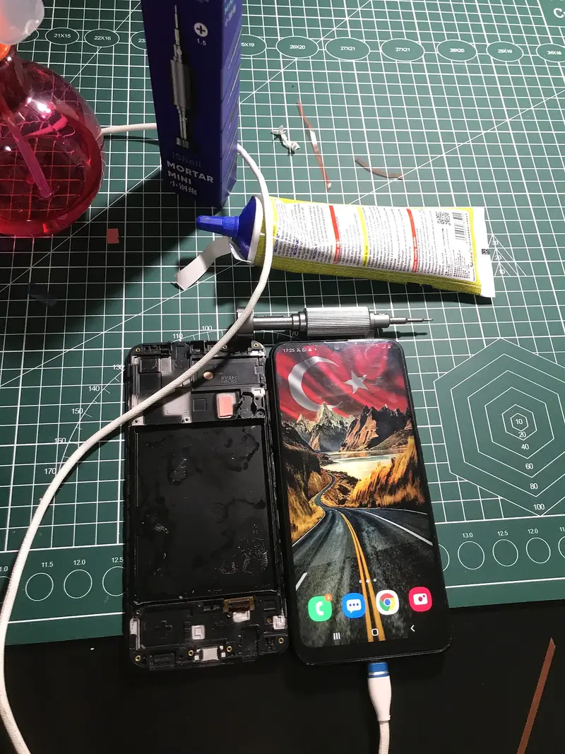 Yeni ekranı takılıp çalıştırılan Samsung telefon, yanında sökülen eski kasa